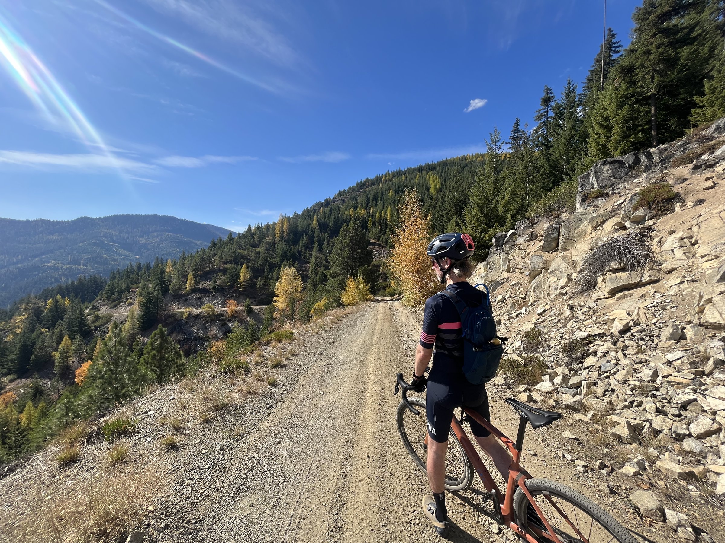 Cyclist paused on mountain gravel road in fall colors