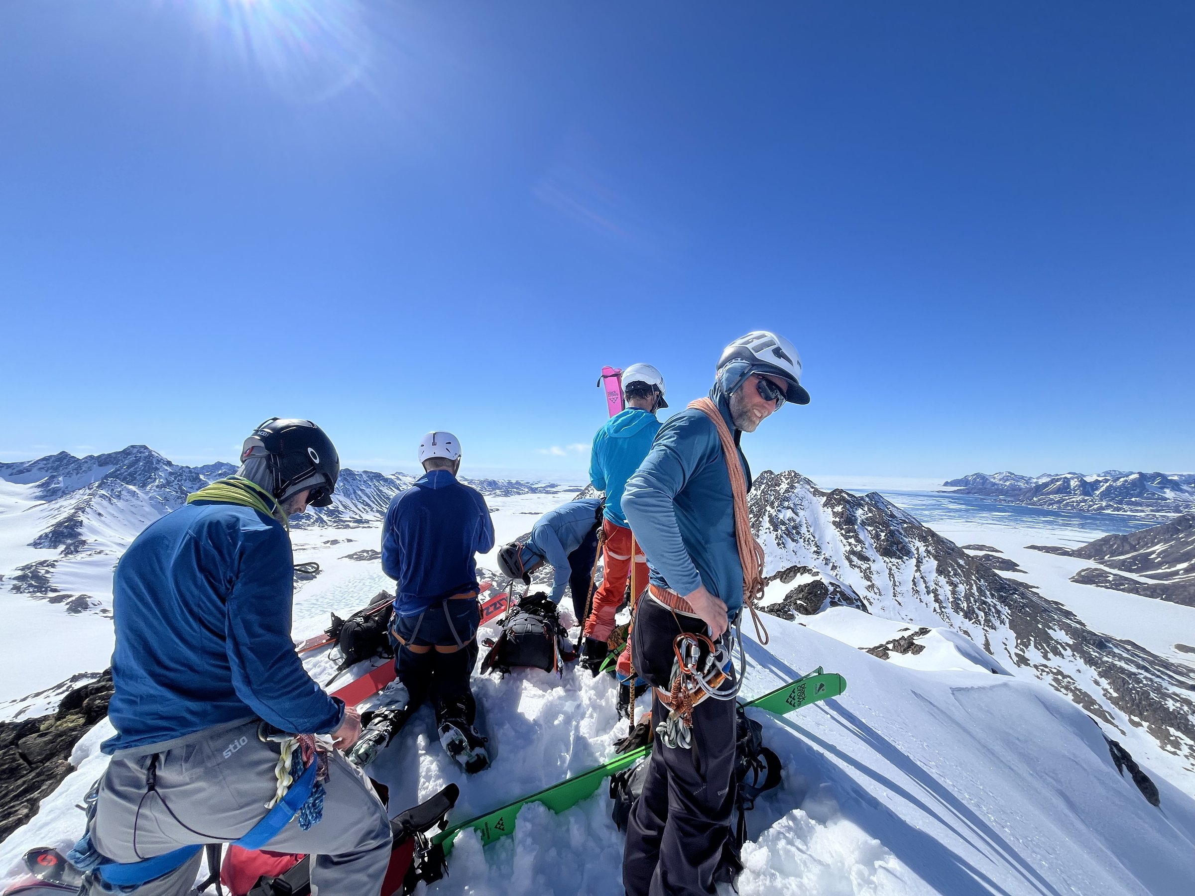Summit group with skis overlooking glaciers in bright sun