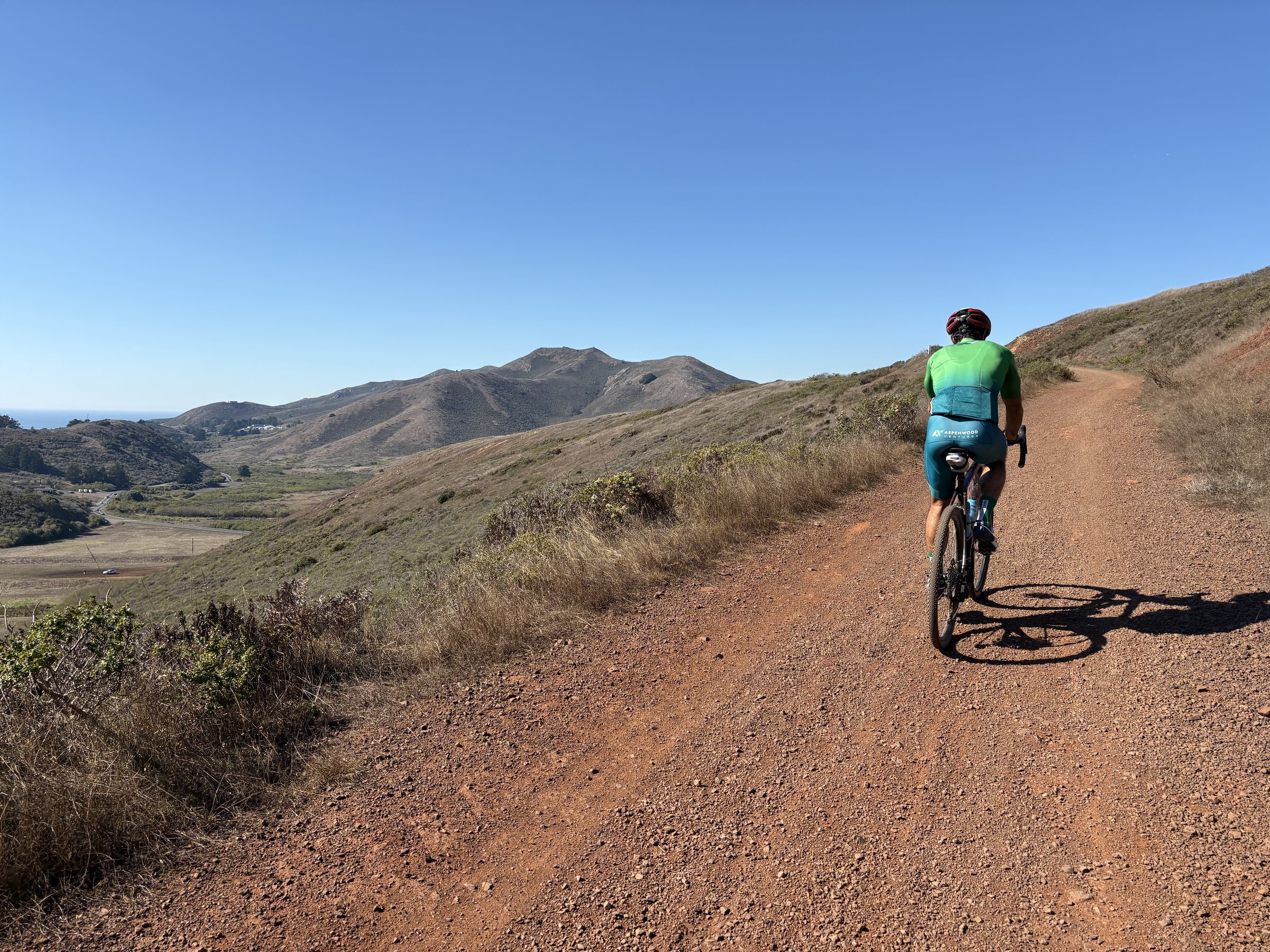 Solo cyclist on red dirt road through rolling hills